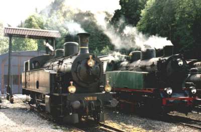 Zwei Dampflokomotiven verschiedener Art, Generation und Herkunft erholen sich nebenan nach der Arbeit